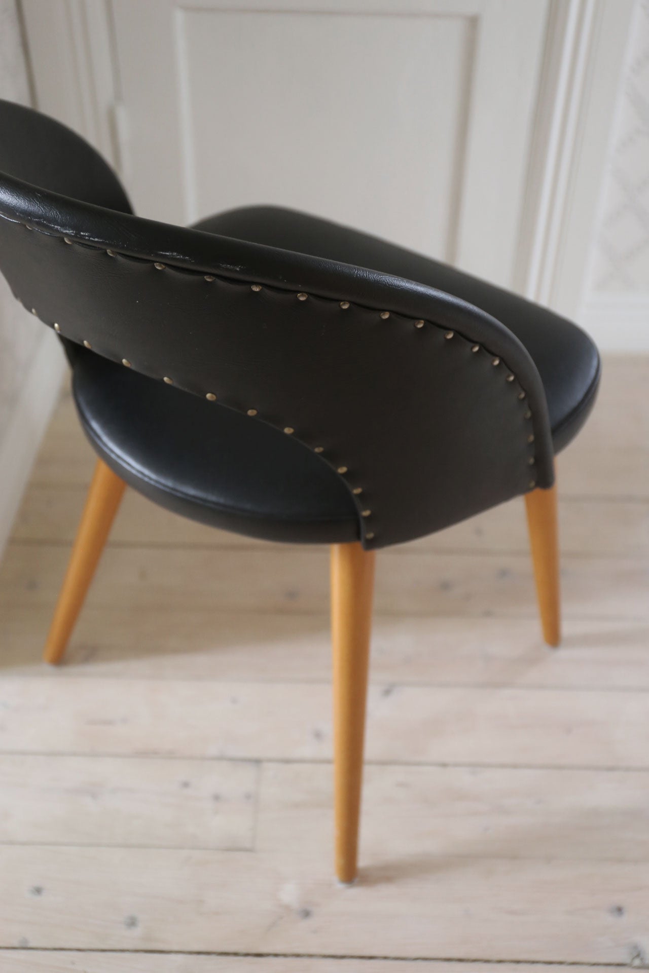 Svart stol i skinnimitation fäst med nitar 50-tal